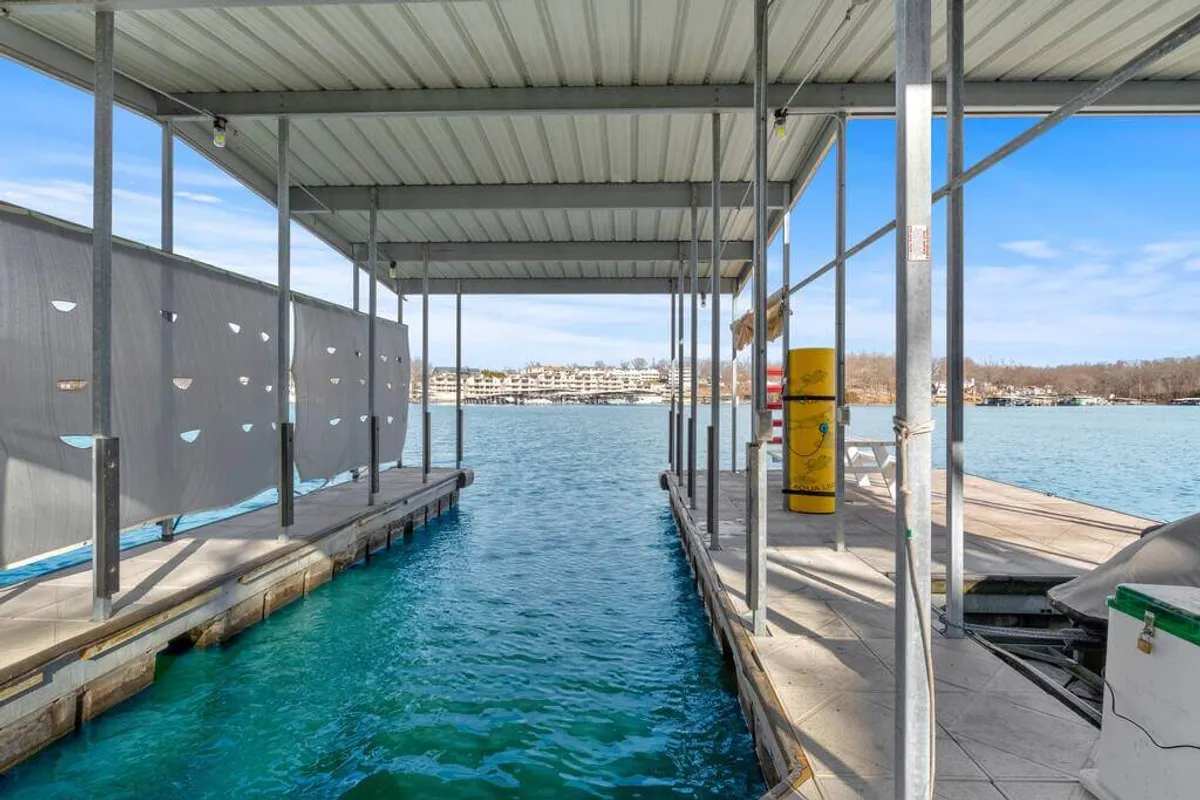 A tranquil view of the private dock extending into the lake, surrounded by the natural landscape and an open sky. The dock is the focal point, emphasizing direct access to the water and opportunities for boating, fishing, or relaxing by the shoreline.
