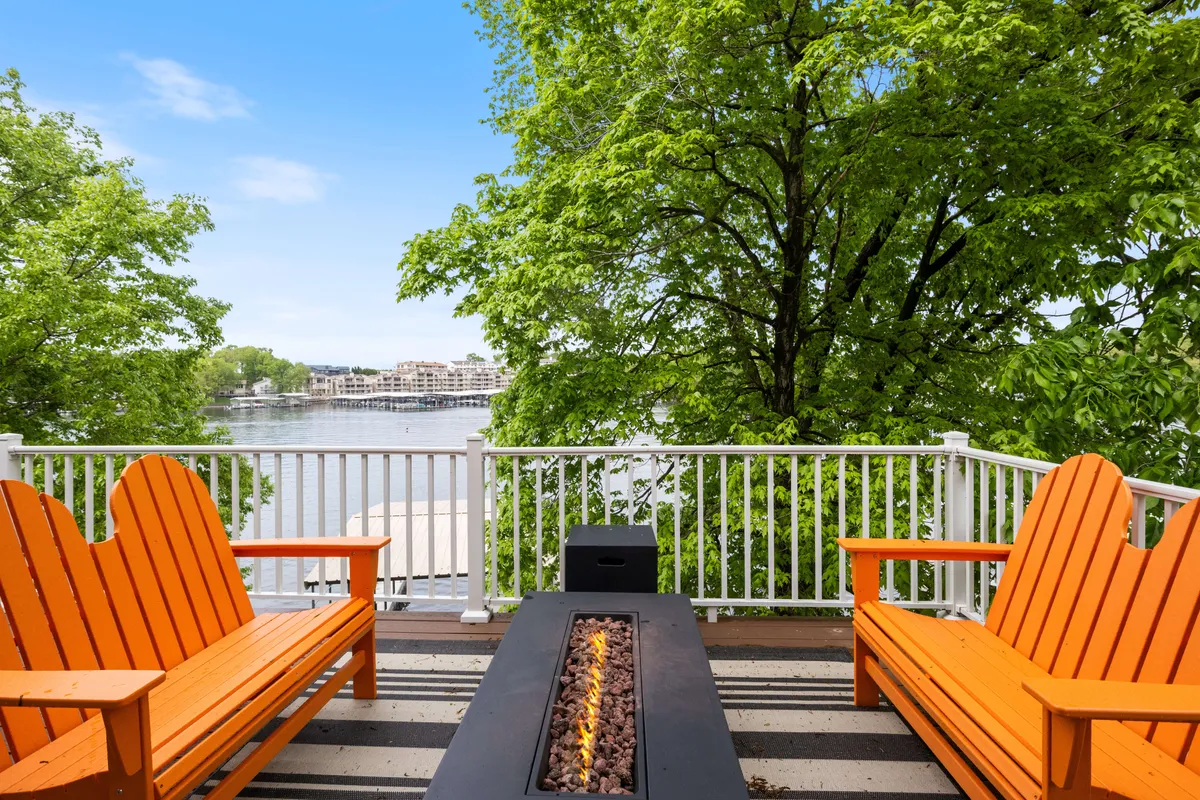 This image features orange Adirondack chairs circling a fire pit overlooking the tranquil water. The warm glow of the fire and the inviting seating create a cozy atmosphere, perfect for relaxing and enjoying the waterfront ambiance together.