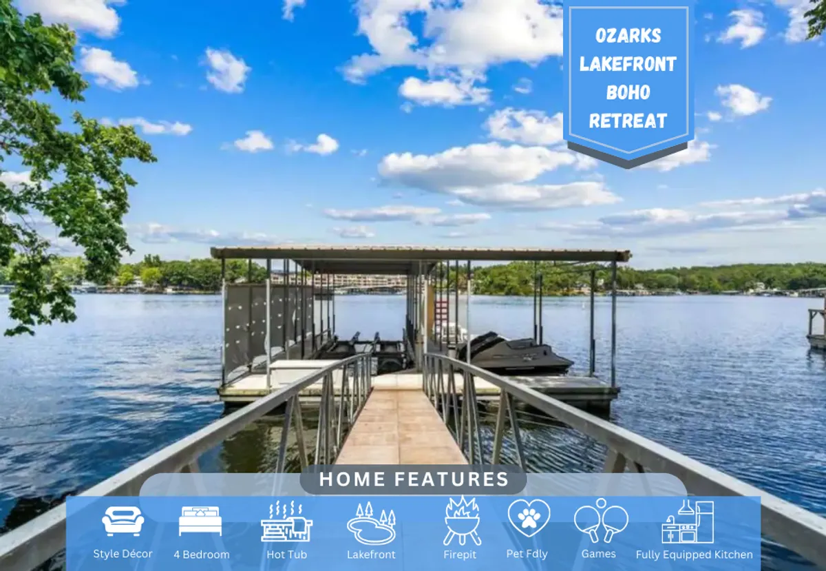 The image showcases the exterior of a single-family lakefront house on Lake of the Ozarks, framed by two spacious decks overlooking the sparkling water. A private dock and boathouse extend into the lake, set against a backdrop of a vibrant blue sky and soft clouds. The inviting scene hints at family gatherings, water sports, fishing, and peaceful moments by the shore.