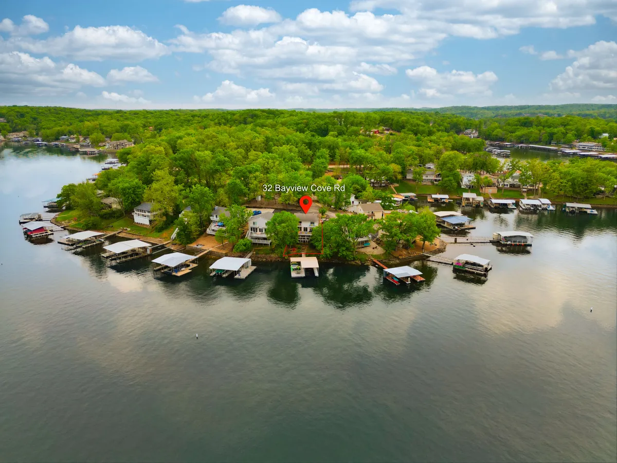 A peaceful lakeside scene showing the property’s proximity to the water, lush greenery, and multiple dock structures. The setting conveys spaciousness and the inviting atmosphere of the lakefront, perfect for swimming, boating, or enjoying family time outdoors.